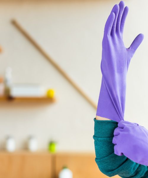 cropped shot of young woman wearing rubber gloves while cleaning house